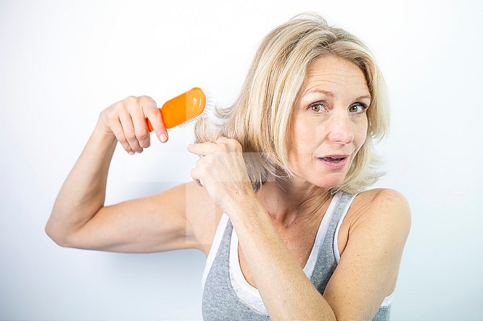 Woman looking at her split ends.