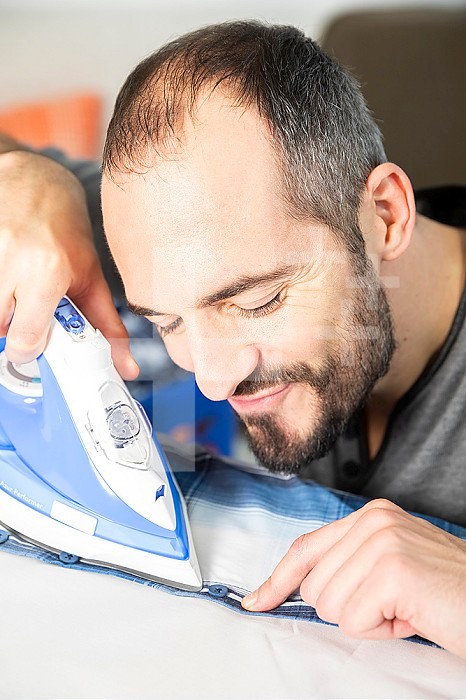 A man carefully ironing his shirt.