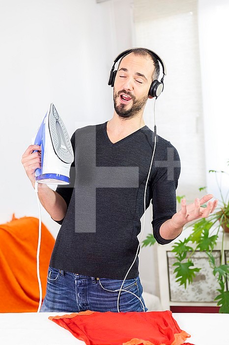 A man ironing while listening to music and singing.