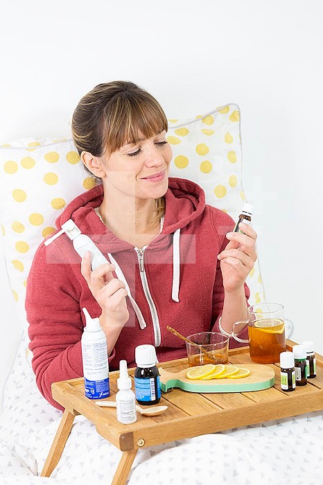 Young woman in bed hesitating between industrial medecine and natural remedies.