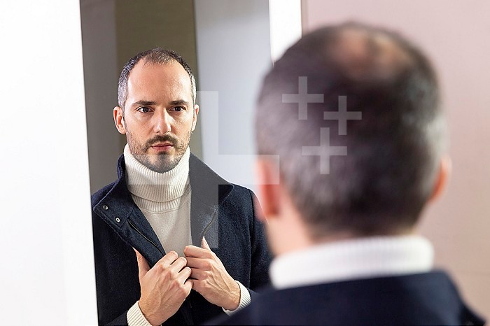 A man looking at himself in the mirror for self-confidence.