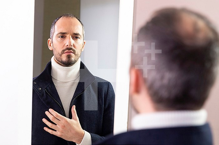 A man looking at himself in the mirror for self-confidence.