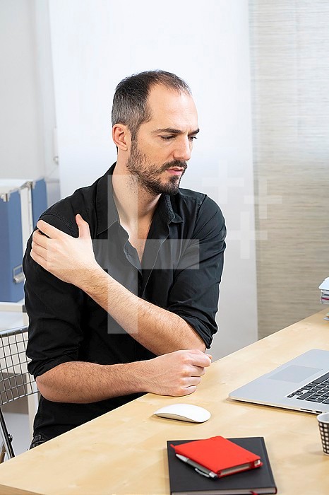 A man at his desk with shoulder pain.