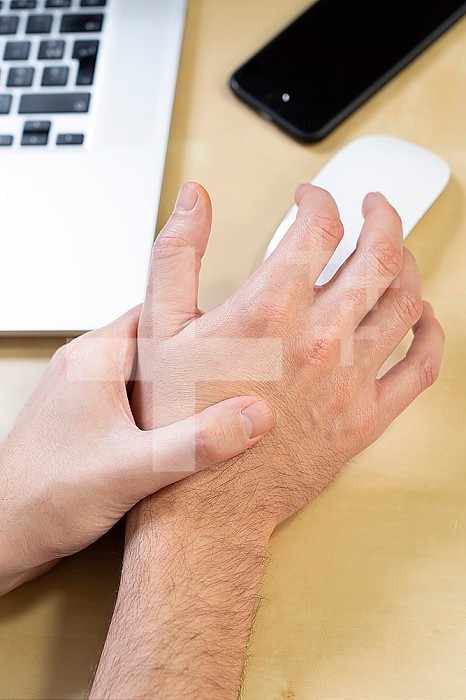 Close-up of a man´s hand experiencing pain due to prolonged use of the mouse.