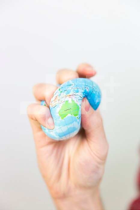 A man gripping a stress ball in the shape of the earth.