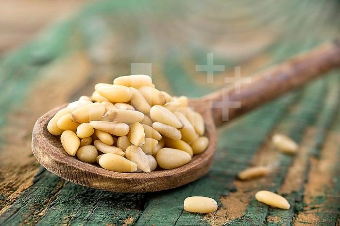 Pine nuts in a wooden spoonon a old blue cracked wood
