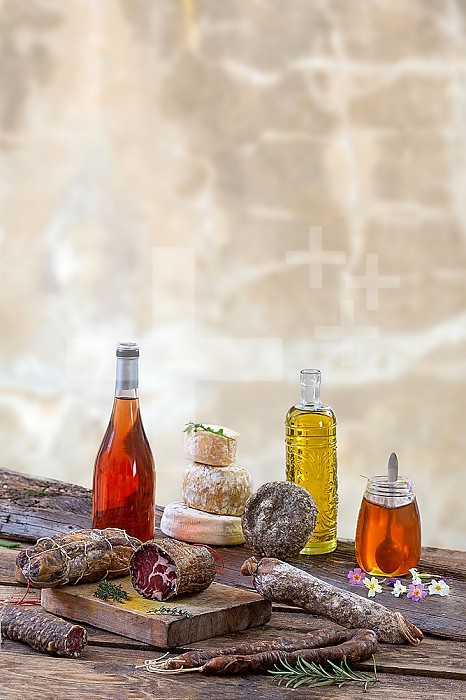 Several variety of traditional Corsican charcuterie with an olive branch and black olives onrustic background.