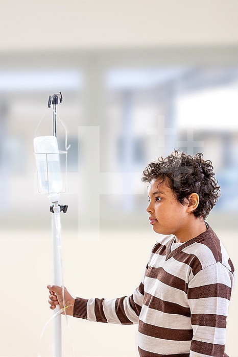Smiling boy, with iv drip standing in corridor hospital, or cliinic