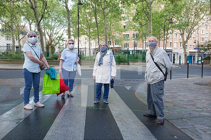 Group of elderly people on a walk authorized within a radius of one kilometer around the home with a protective mask respecting the social differentiation against the coronavirus in Paris.