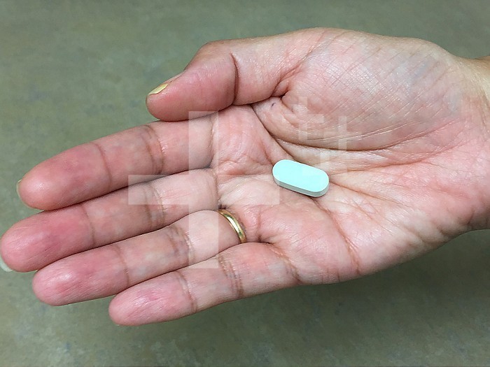 A woman holds an antiretroviral drug to treat HIV infection in her palm. Credit: NIAID