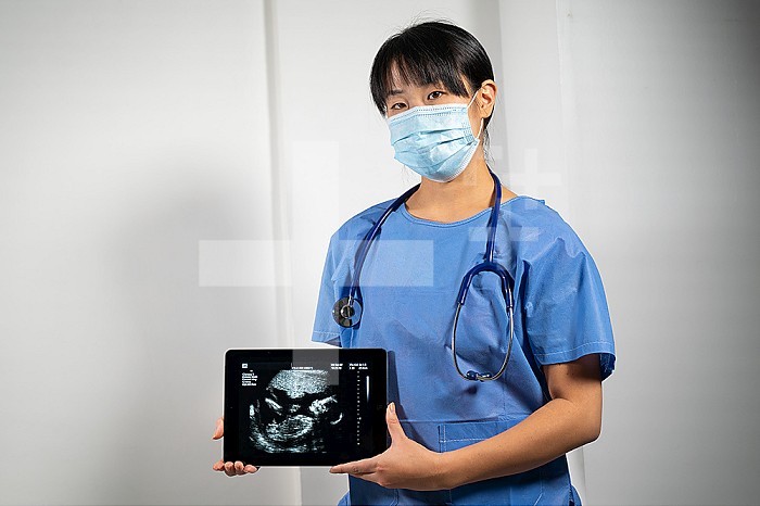 Female doctor holding a screen with fetal ultrasound