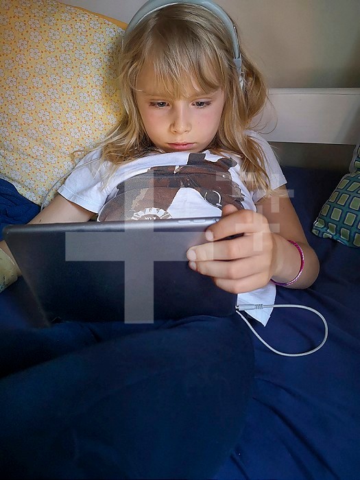 8 year old girl watching a cartoon on a touch pad, France.