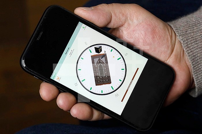 Muslim using a Qibla compass on a smartphone to indicate the direction of Mecca. France.