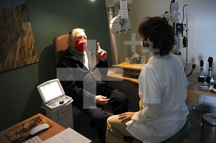 Ophthalmology office. Masked patient and doctor - Covid 19 in consultation. Refractive telescope, slit lamp, fundus, AMD, diabetes of the eye, retinal scanner, Volk lens, Cover test, glasses, blur. Old person. .