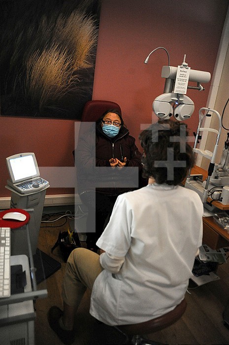 Ophthalmology office. Masked patient and doctor - Covid 19 in consultation. Refractive telescope, slit lamp, fundus, AMD, diabetes of the eye, retinal scanner, Volk lens, Cover test, glasses, blur. Old person. .