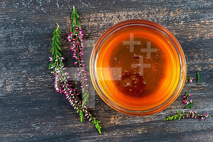 A saucer full of heather honey and a sprig of heather.