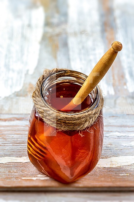 Single jar of honey containing a wooden stick.