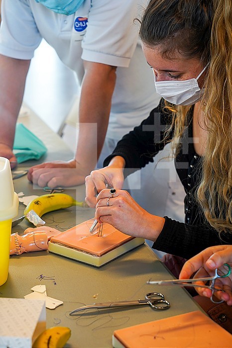 5th year students during a sewing workshop. The students learn the gestures of suturing on false epidermis or bananas. A professor of emergency medicine directs the suturing course.