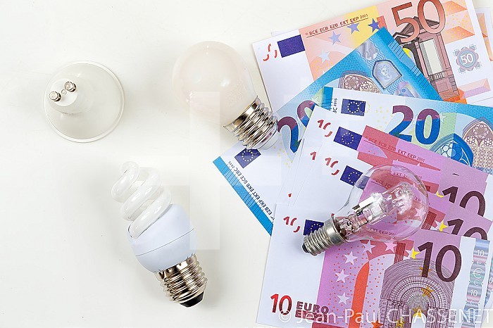 Light bulbs arranged on banknotes, energy cost.