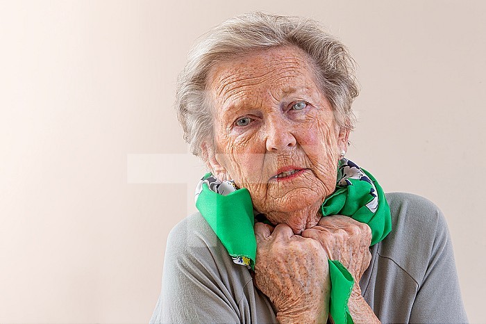 Sick elderly woman with a scarf around her neck.