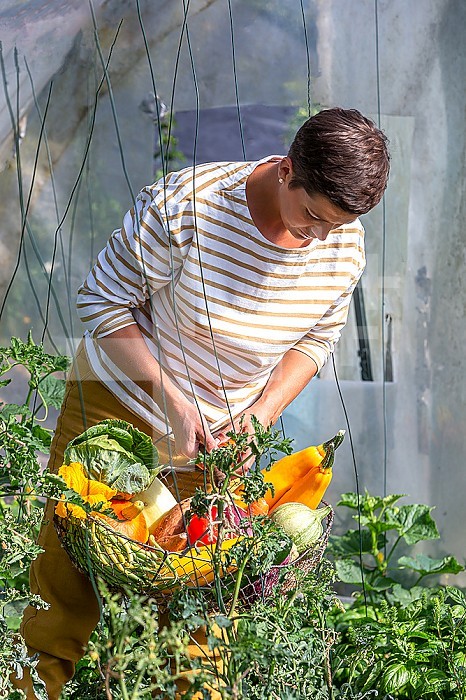 Young woman standing the basket filled with vegetables.