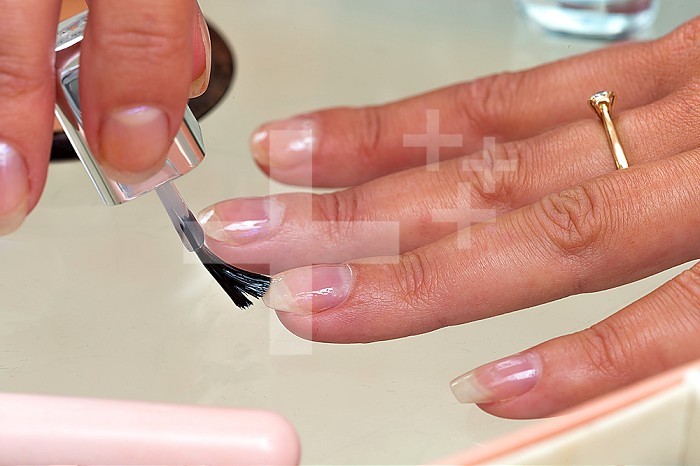 Woman applying transparent veni on her nails.