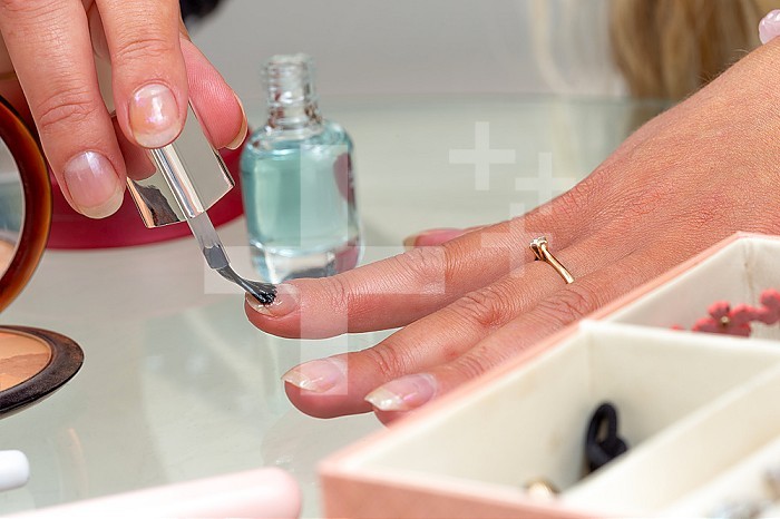 Woman applying transparent veni on her nails.