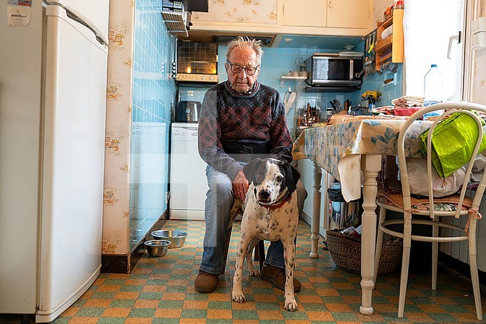 Loneliness of the elderly person, senior living alone with their dog in their kitchen.