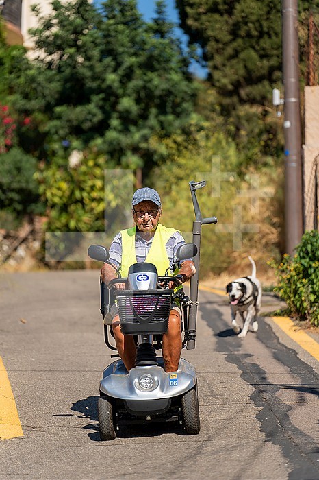90-year-old senior walking on his electric scooter, with his dog.