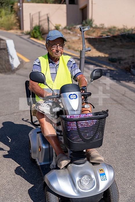 90-year-old senior walking on his electric scooter, with his dog.
