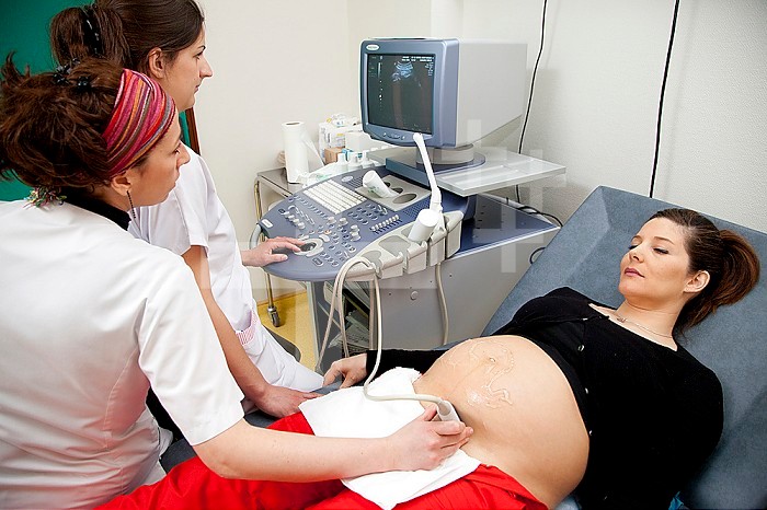 Hospital. Maternity. 4th year student midwife performing a prenatal ultrasound under the supervision of a midwife. 24 weeks, 6 months pregnant woman.