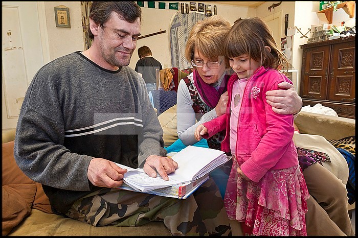 ASE - Childhood Social Assistance. Oceane in Isabelle´s arms shows her class homework to her father. EDITORIAL USES ONLY.