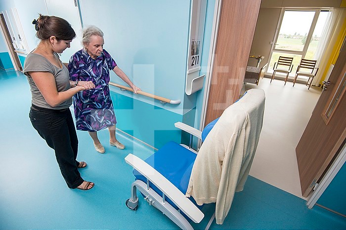 EHPAD - Physiotherapist performing walking exercises with an elderly resident in the hallway.
