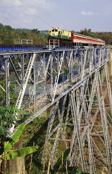 Passenger train crossing high trestle bridge viaduct, Indonesia.
