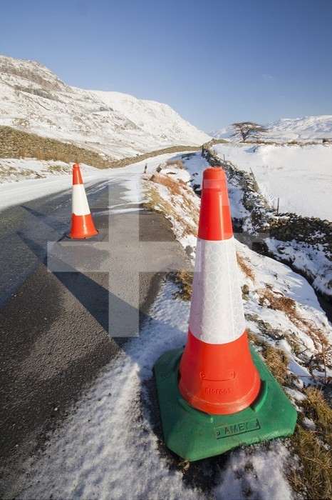 Traffic cones on the road to Kirkstone Pass in the Lake District in winter snow, UK