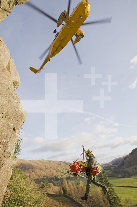 An RAF Sea King Helicopter evacuates a seriously injured climber with a broken femur from a mountain rescue site in the Langdale Valley, Lake District, UK