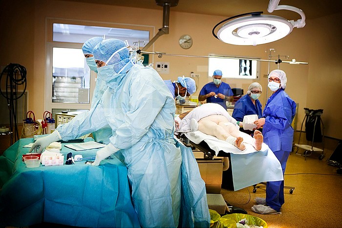 Reportage in the Osteoarticular Infections Referral Centre (CRIOA) at Diaconesses Croix Saint Simon hospital in Paris. Septic surgery, removing an internal fixation in the ankle following an infection. To avoid infection spreading, the operating theatre team wear scrub overalls that have to be taken off when leaving theatre.