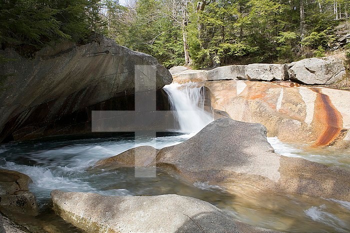 The Pemigewasset River eroding granite bedrock and creating potholes as it flows through The Basin  in Franconia Notch State Park, New Hampshire, USA. Note the mineral stains along some of the rocks.