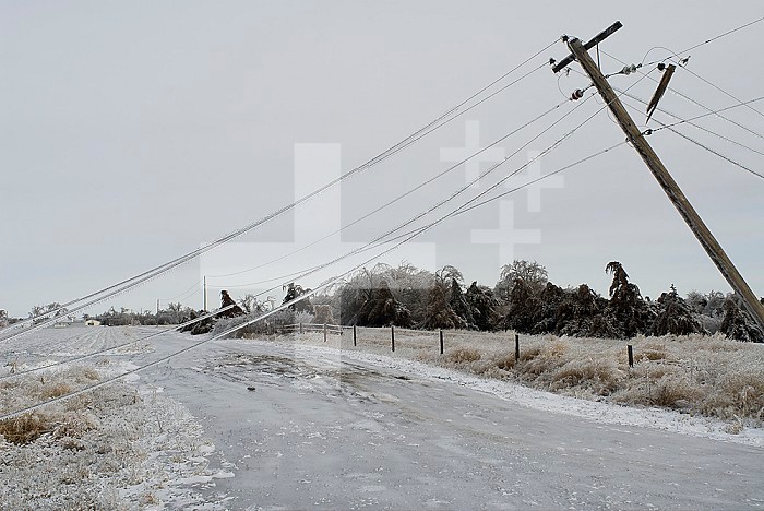 Damaged electrical and communication lines hang over an ice-covered road during freezing rain storm in Kearney, Nebraska.