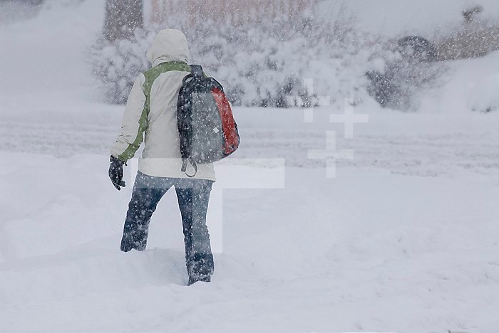 A pedestrian walks through deep snow wearing cold weather clothing during a winter storm in northern Colorado.