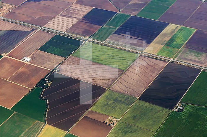 Aerial view of rectangular, square, and contoured farm fields, some fallow, some in use, and with a variety of crops, Sacramento Valley, California, USA.