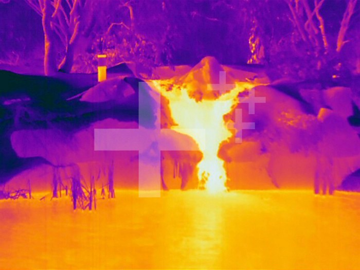 Thermogram of a waterfall flowing into a pond on a cold winter day showing that water is warmer than the surrounding land. The colors show temperature variation with the temperature scale running from white (warmest) through yellow, orange, red, purple and black (coldest).