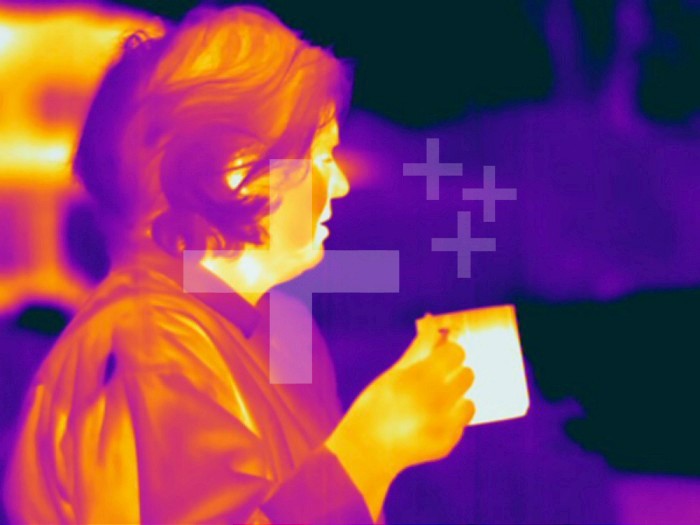 Thermogram of a woman drinking a hot beverage on cool morning. The colors show temperature variation with the temperature scale running from white (warmest) through yellow, orange, red, purple and black (coldest).