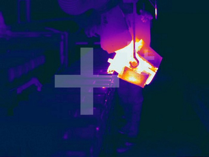 Thermogram showing temperature variation of a Metal Foundry plant pouring molten metal into mold. The colors show temperature variation. The temperature scale runs from white (warmest) through yellow, orange, red, purple and black (coldest).