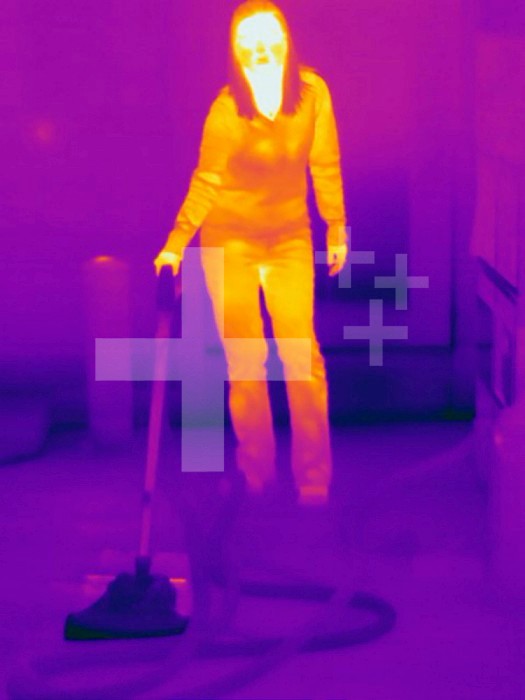 Thermogram - Female vacuuming - The colors show temperature variation. The temperature scale runs from white (warmest) through yellow, orange, red, purple and black (coldest)