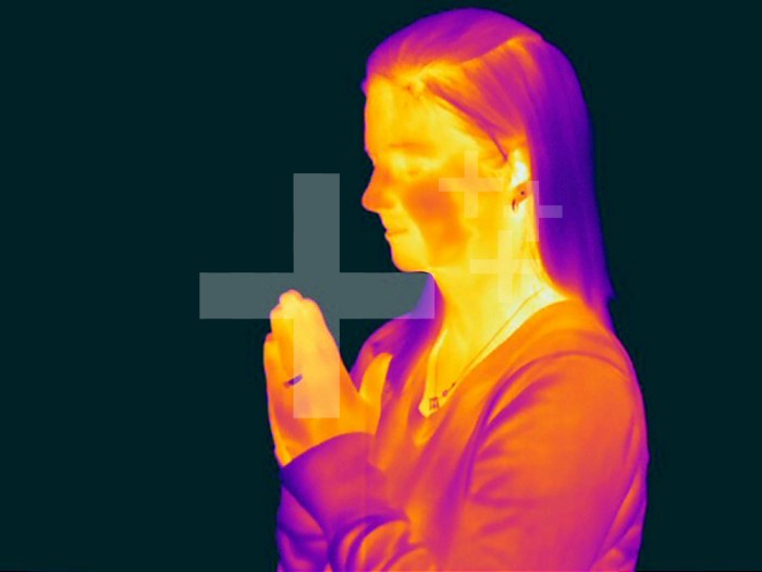 Thermogram - Female praying - The colors show temperature variation. The temperature scale runs from white (warmest) through yellow, orange, red, purple and black (coldest)