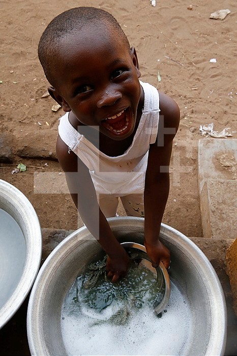 African primary school (Togo). Pupil having fun while doing the dishes after lunch.