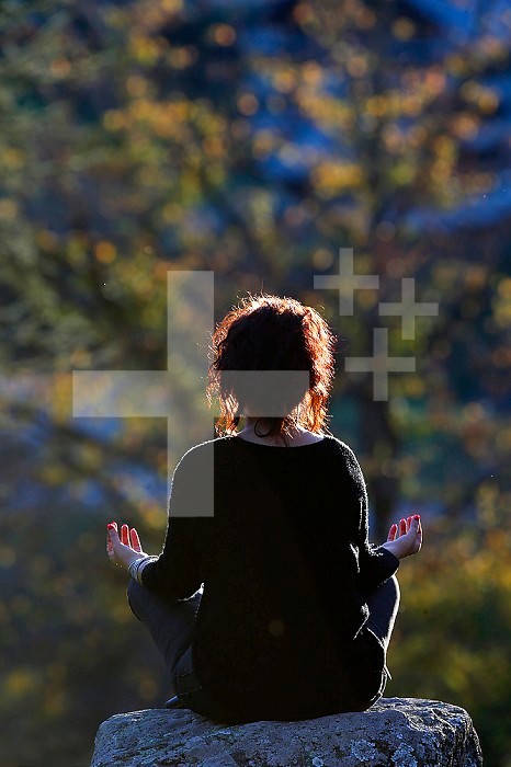Woman sitting on a rock in Lotus Position.