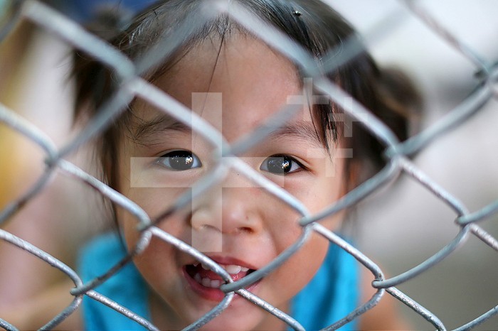 Portrait. Lao girl behind a fence.