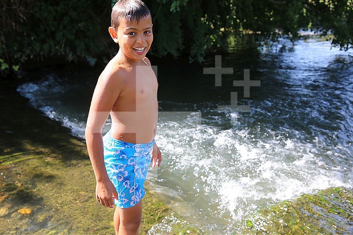 Boy wading in a river.